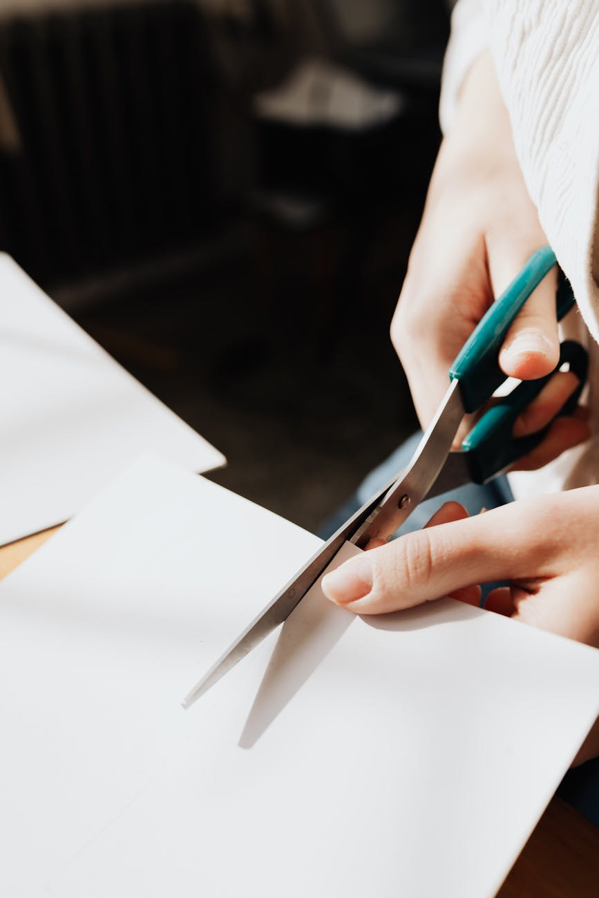 crop young craftswoman cutting paper sheet